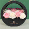 Pink roses and white carnations arranged in a round black gift box