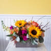 Mixed bouquet with sunflowers, peach roses, and magenta flowers in a rectangular box