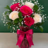 Pink and white roses in a magenta vase with a ribbon bow