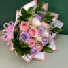 Bouquet of pink, lavender, and white roses with baby’s breath and ribbon wrap