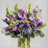 Tall bouquet of purple and pink flowers in a clear glass vase