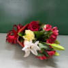 Bouquet of red roses, white lilies, and pink alstroemeria with a red ribbon