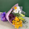 Bouquet of yellow, white, and purple flowers wrapped in pink paper
