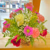 Mixed bouquet in a woven basket with roses, carnations, and daisies