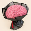 Large bouquet of pink roses wrapped in black paper with a red ribbon