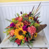 Colorful bouquet with sunflowers, roses, and carnations in a woven cone wrap