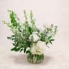 White rose arrangement in a round glass vase with tall green stems