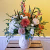 Mixed floral arrangement in a white ceramic pitcher vase