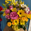 Mixed bouquet of pink, yellow, and white flowers in a yellow vase