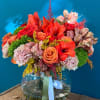Bouquet of red and peach flowers in a clear glass vase