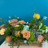 Mixed floral arrangement in a wooden box with peach roses and blue hydrangeas
