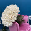 Large bouquet of white roses resting on a pink chair