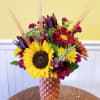 Mixed bouquet with sunflowers and burgundy blooms in a textured vase