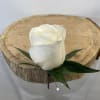Single white rose with green leaves on a wood slice