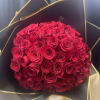 Round bouquet of red roses wrapped in black and gold paper