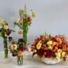 Autumn centerpiece of orange and yellow flowers in a white pumpkin with three smaller mixed bud vases.