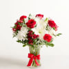 Red and white mixed bouquet in a clear glass vase with a red ribbon