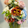 Mixed bouquet of roses, chrysanthemums, and hydrangeas in a glass vase