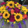 Bright mixed bouquet with sunflowers, roses, and purple blooms in a metal bucket