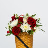 Red roses and white daisies in a woven basket with a black ribbon