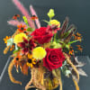 Red roses and mixed fall flowers in a glass vase