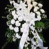 White funeral spray with lilies, roses, and carnations on a black background