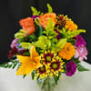 Mixed bouquet of roses, lilies, and chrysanthemums in a glass vase