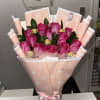 Pink rose bouquet wrapped in peach paper with a satin bow and chocolates