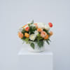 Peach and cream roses and ranunculus mingle in a lush, rounded cluster-an