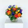 Colorful bouquet of roses, tulips, and orange blooms in a glass vase