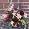 Mixed bouquet in a decorated vase with roses, carnations, and magenta daisies