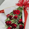 Bouquet of red roses wrapped in white paper with a red ribbon