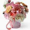 Pink and white mixed flowers arranged in a pink hatbox with a satin ribbon and card