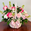 Pink roses and white daisies in a white basket with a pink ribbon