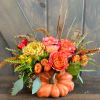 Orange pumpkin container with pink and orange flowers and dried accents