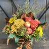 Autumn bouquet with yellow chrysanthemums, pink roses, and apples in a glass vase