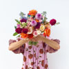 Person holding a colorful mixed bouquet of roses and other blooms