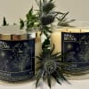 Two scented candles with floral labels and thistle-like stems
