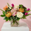 Mixed bouquet of pink, white, and orange flowers in a clear glass vase