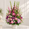 Tall pink and purple flower arrangement in a white basket vase