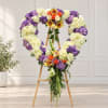 Heart-shaped floral wreath on a wooden easel with purple, white, and orange flowers