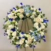 Large floral wreath with white roses and blue flowers on a stand