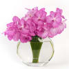 Pink orchids arranged in a round glass vase with water