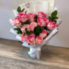 Bouquet of pink roses wrapped in white paper with a ribbon