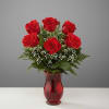 Red roses arranged in a red glass vase with baby's breath
