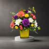 Colorful mixed flower arrangement in a yellow glass vase