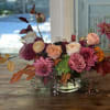 Mixed pink and peach flower arrangement in a clear glass bowl