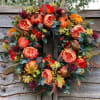 Autumn wreath with orange roses and small pumpkins on a rustic wood background