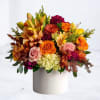 Mixed bouquet of orange, pink, and yellow flowers in a white cylinder vase