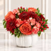 Orange and red floral arrangement in a white vase